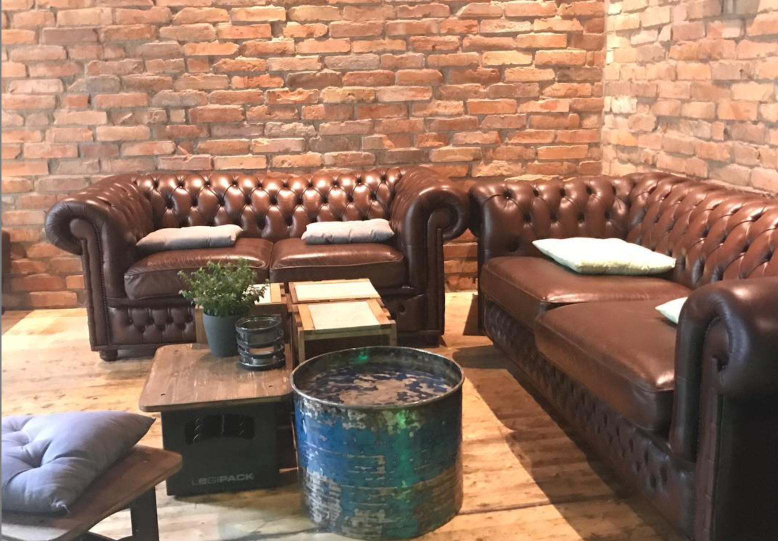 Chesterfield group with concrete and wooden tables in front of brick wall